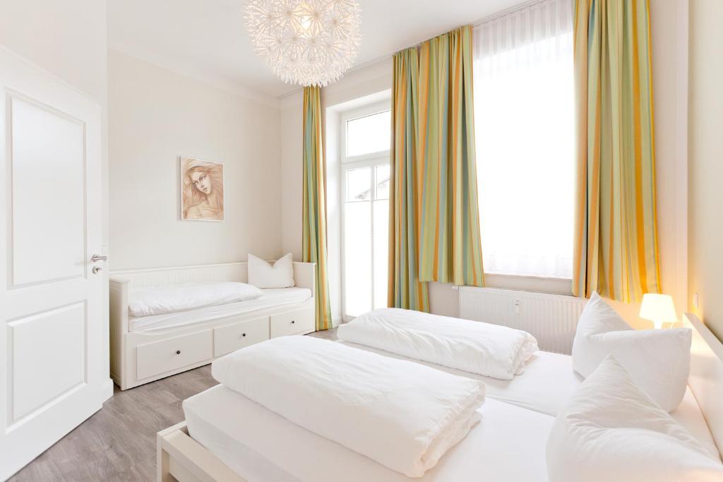 a white room with two beds and a chandelier at Ferienwohnungen Familie Glasner in Binz