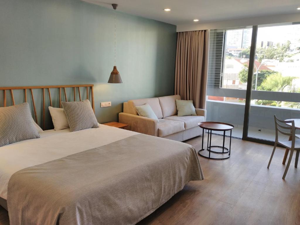 um quarto com uma cama, uma cadeira e um sofá em Apartamentos Ciudad Jardín em Las Palmas de Gran Canaria