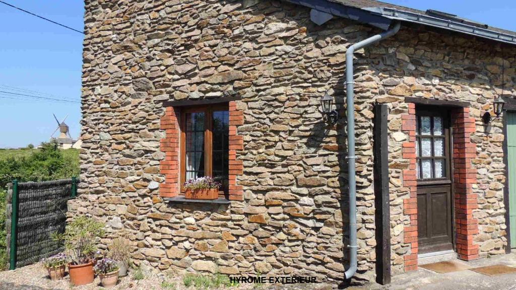 een stenen gebouw met twee ramen en een deur bij Gîte Hyrom 5 Places Moulin de la Placette in Faye-dʼAnjou