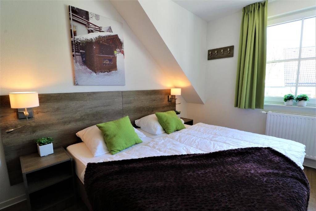 溫特貝格的住宿－UplandParcs Residence Astenberg，一间卧室配有一张带绿色枕头的大床