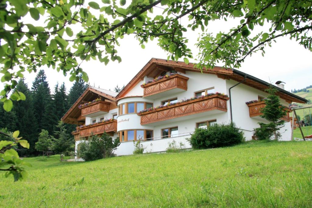 une maison avec des balcons en bois sur un champ verdoyant dans l'établissement Bed & Breakfast Untermüllerhof, à Maranza