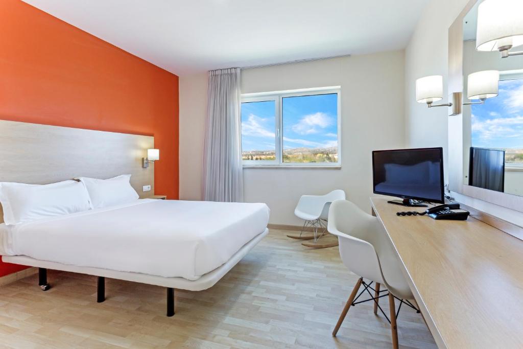 ラス・ロサス・デ・マドリードにあるB&B HOTEL Madrid Las Rozasのベッド、デスク、コンピュータが備わるホテルルームです。