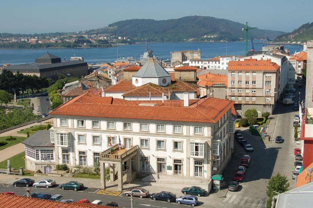 un gran edificio blanco con techo rojo en una ciudad en Parador de Ferrol, en Ferrol