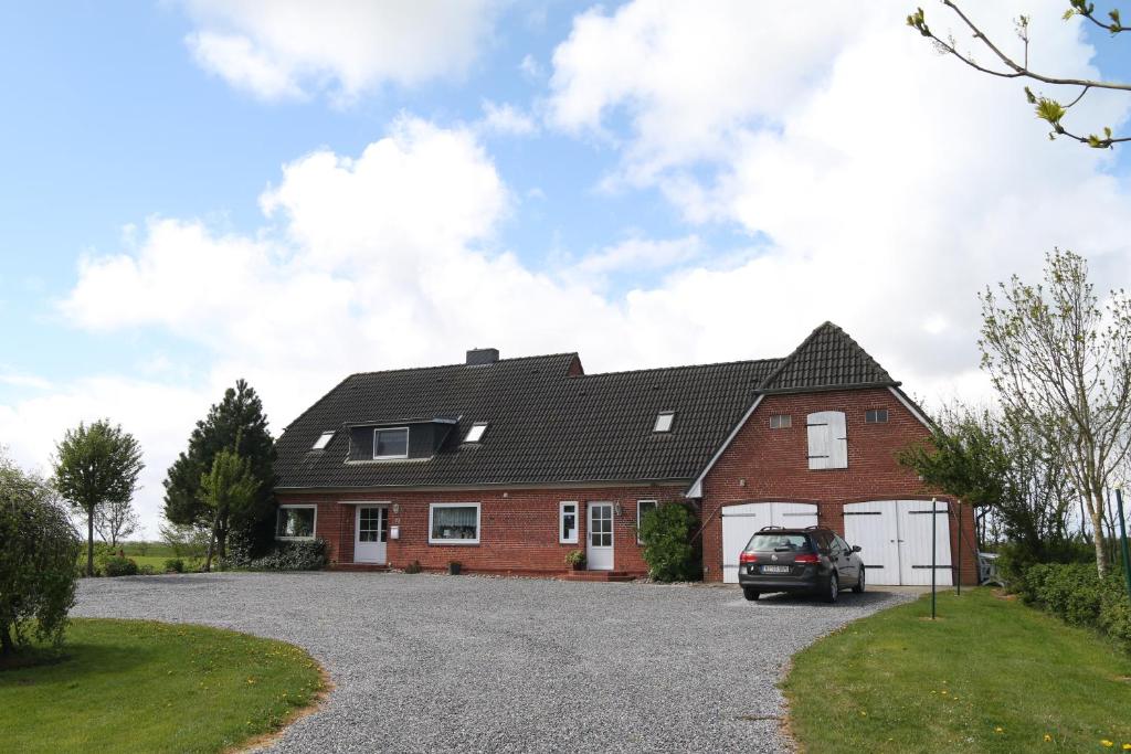 a house with a car parked in the driveway at Ferienwohnung Süderdeich in Neukirchen