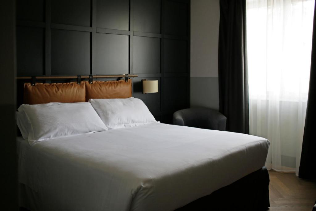una camera da letto con un grande letto bianco e una finestra di c-hotels Club House Roma a Roma