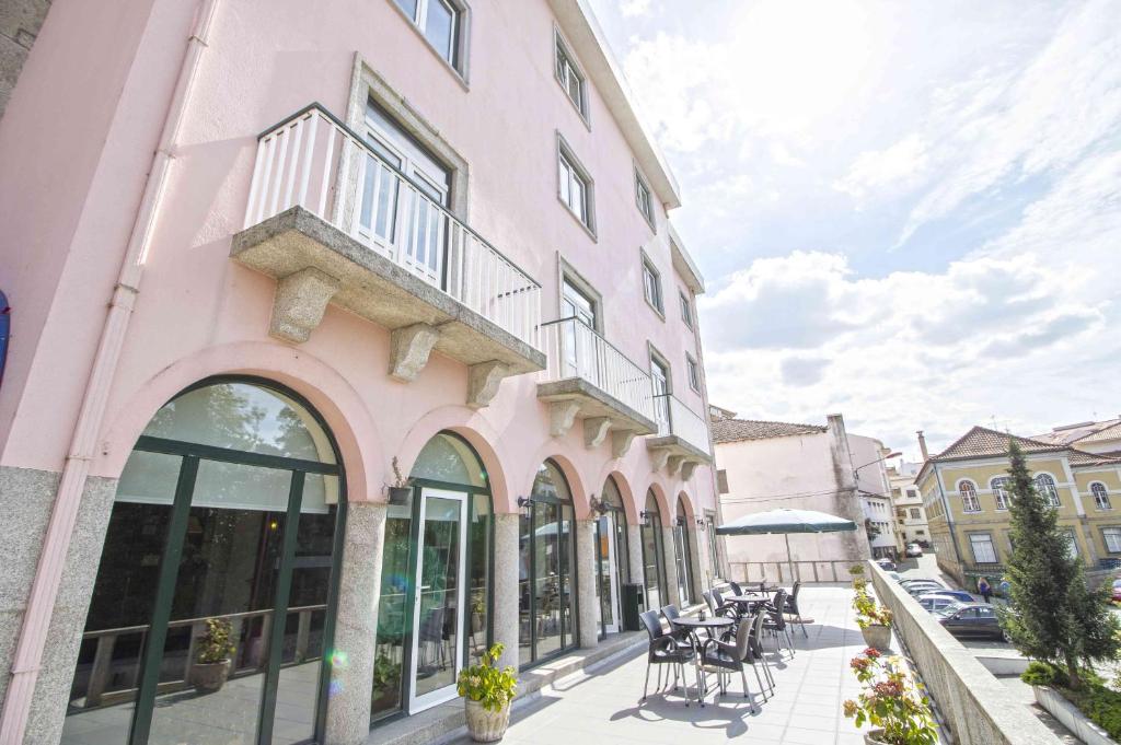 um edifcio cor-de-rosa com uma varanda numa rua em Hotel Eurosol Gouveia em Gouveia