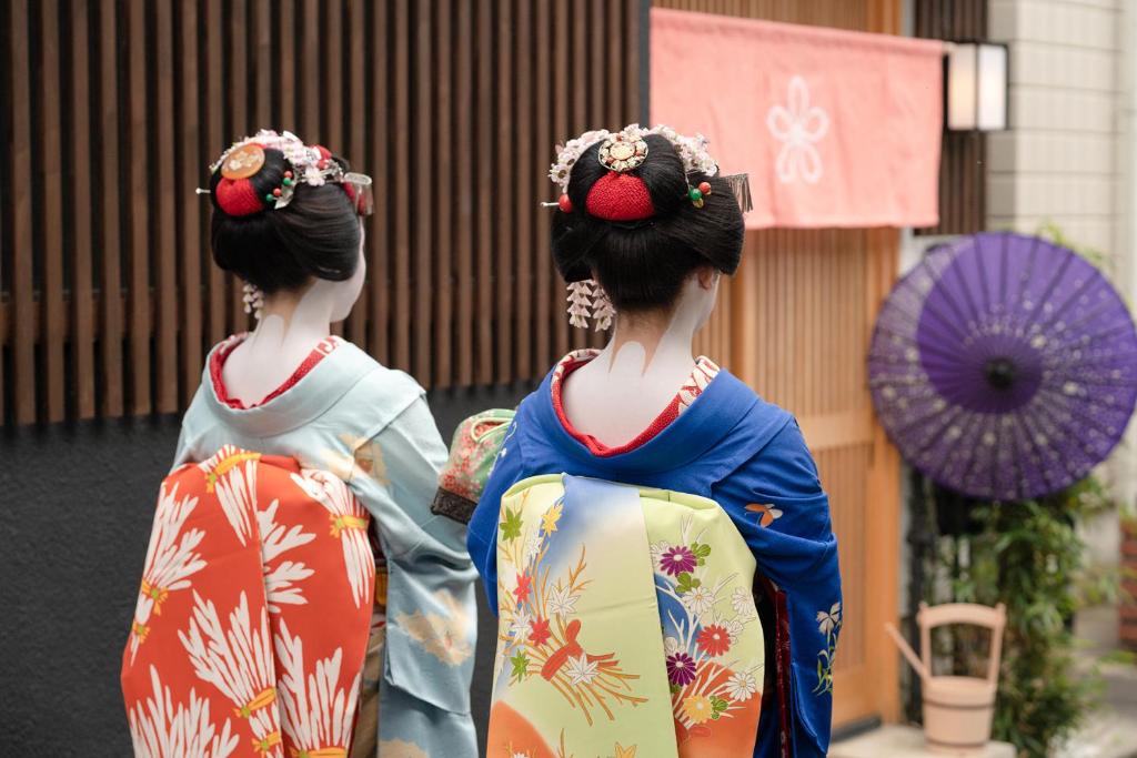 dos mujeres japonesas en kimonos caminando por una calle en Stay SAKURA Kyoto Toji Machiya, en Kioto
