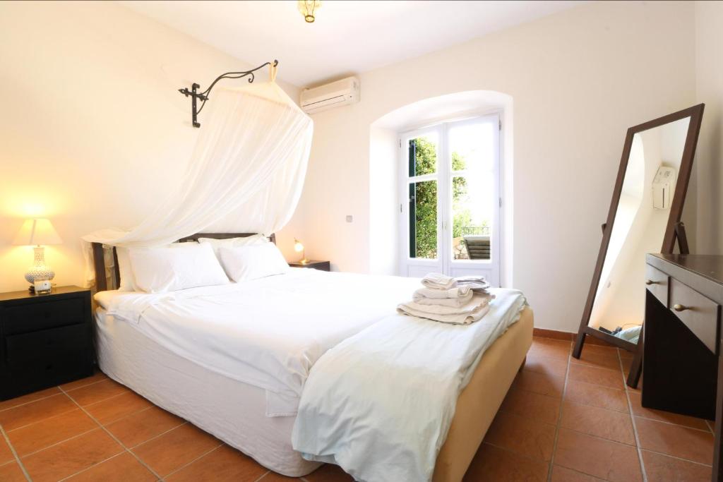 a bedroom with a white bed and a window at The Olive Press Villa in Áyios Pandeleḯmon