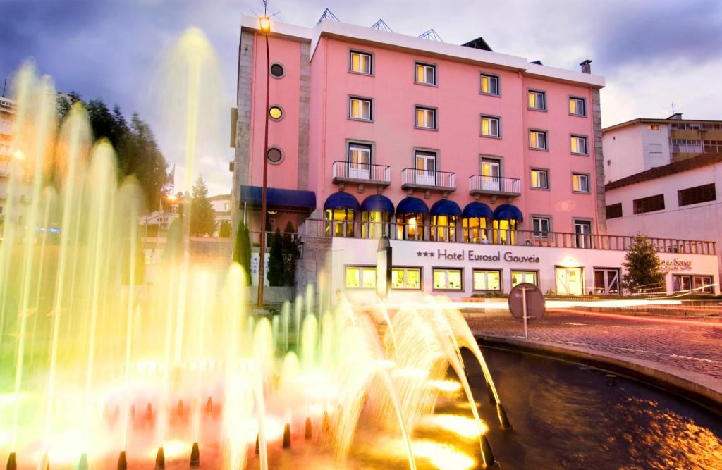 uma fonte de gua em frente a um edifcio rosa em Hotel Eurosol Gouveia em Gouveia