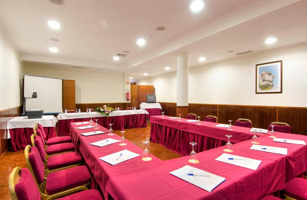 uma sala de conferncias com mesas e cadeiras vermelhas e um quadro branco em Hotel Eurosol Gouveia em Gouveia