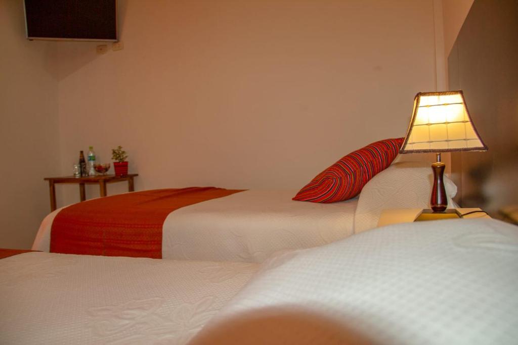 a hotel room with two beds with a lamp on it at Pandora hotel colca in Chivay