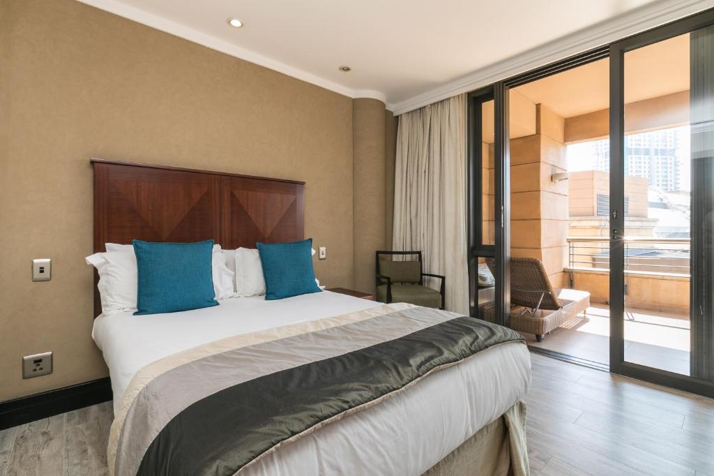 um quarto com uma cama grande e almofadas azuis em 207 Raphael Penthouse em Joanesburgo