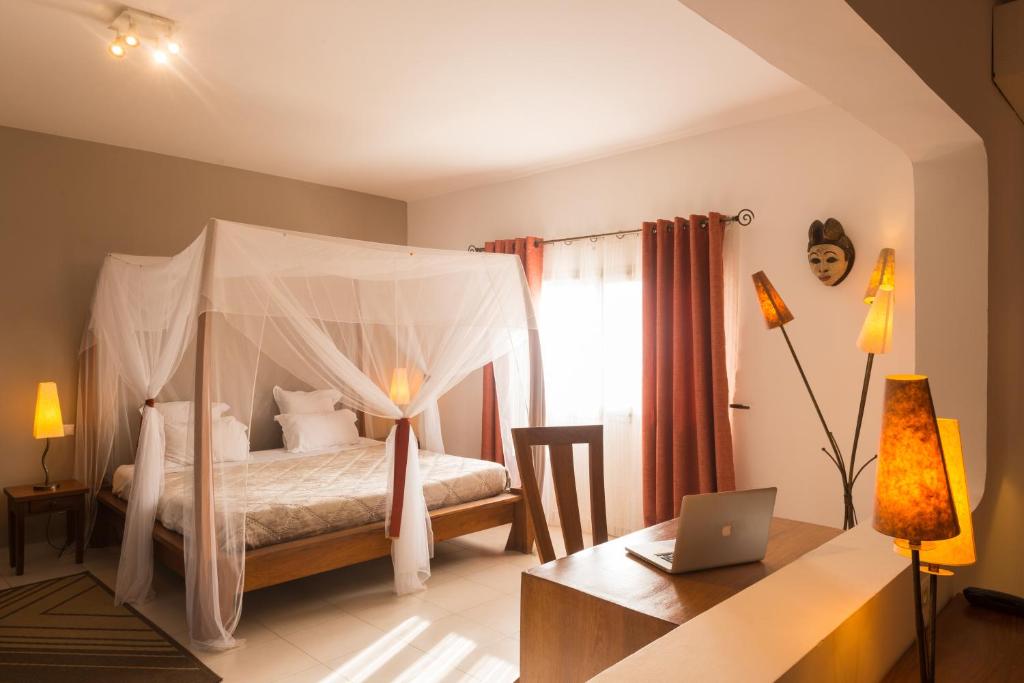 a bedroom with a bed and a desk with a laptop at La Résidence in Dakar