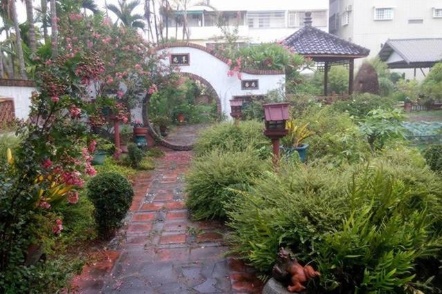 屏東市的住宿－依水園中式花園民宿  ，花园,花园内有种有花草的砖路