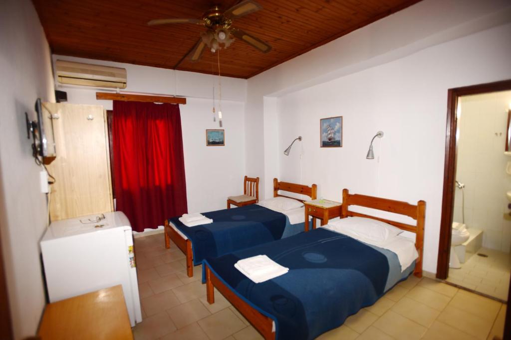 two beds in a room with a red curtain at Stelios Rooms to Rent in Chania Town