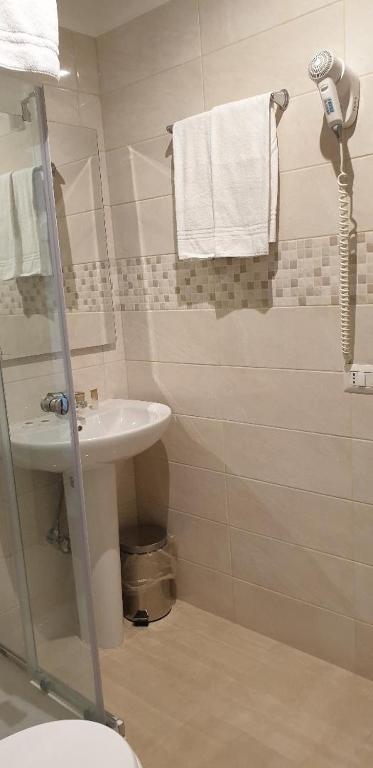 a bathroom with a sink and a shower with towels at Hotel Chopin in Fiumicino