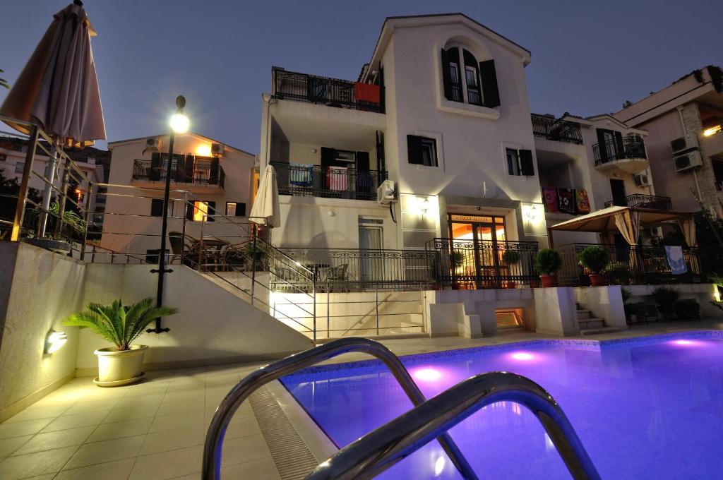 ein Hotel mit einem Pool vor einem Gebäude in der Unterkunft Vila Đurić - Ex Hotel Đurić in Petrovac na Moru