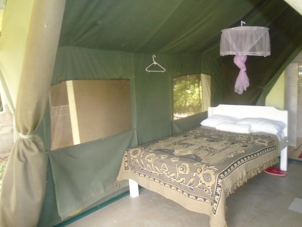 een slaapkamer met een bed in een groene tent bij Rhino Tourist Camp in Ololaimutiek