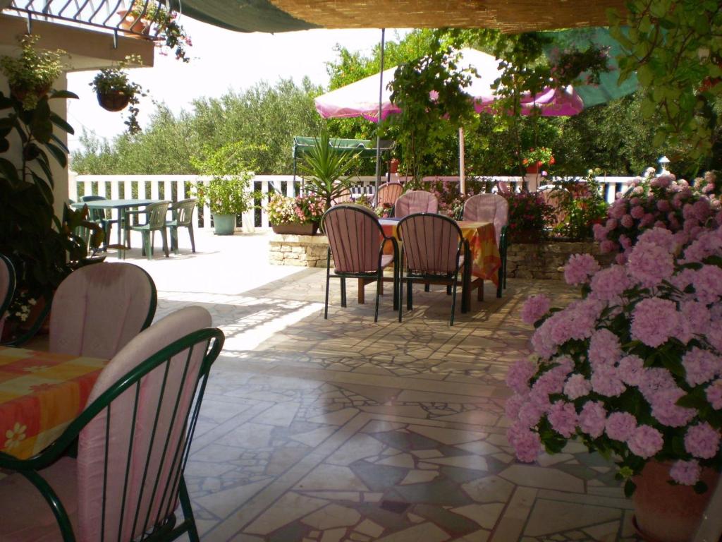 eine Terrasse mit Tischen, Stühlen und rosa Blumen in der Unterkunft Apartments Nada in Sućuraj