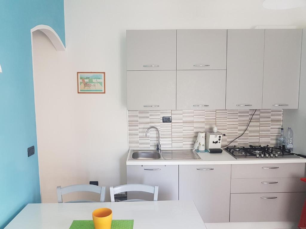 a kitchen with white cabinets and a table with chairs at Casa Marcella in Cetraro