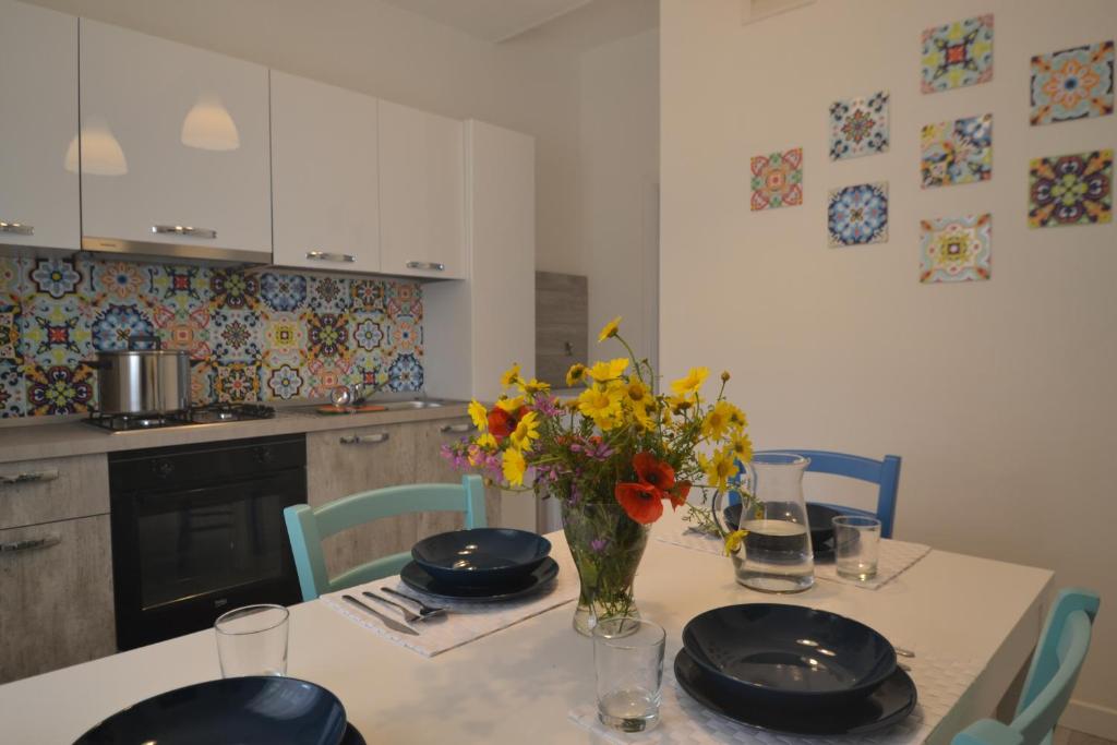 una cocina con una mesa con un jarrón de flores. en Case degli Avi, camere nel Borgo marinaro, en Pozzallo