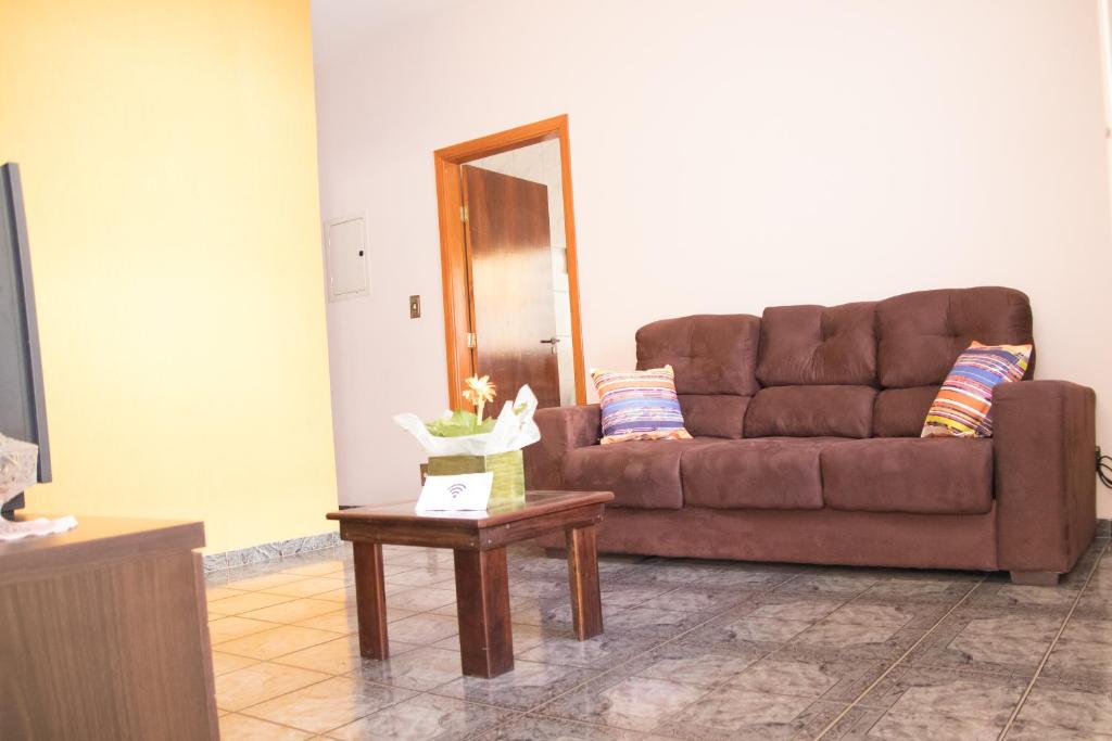 a brown couch sitting in a living room with a table at Casa confortável em Guaratinguetá in Guaratinguetá