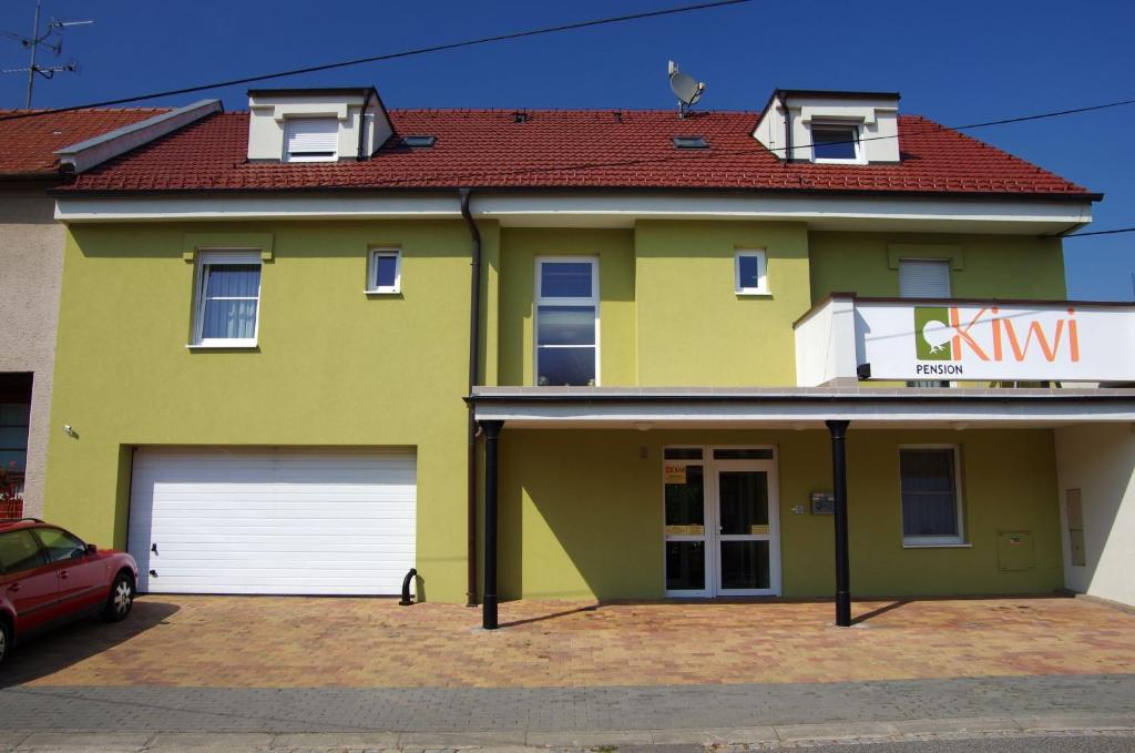 a yellow house with two garage doors and a car at Pension Kiwi in Mikulov