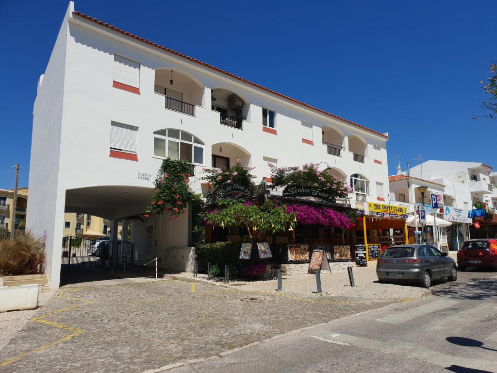 a white building with flowers on the side of it at Apartment on The Strip Albufeira in Albufeira