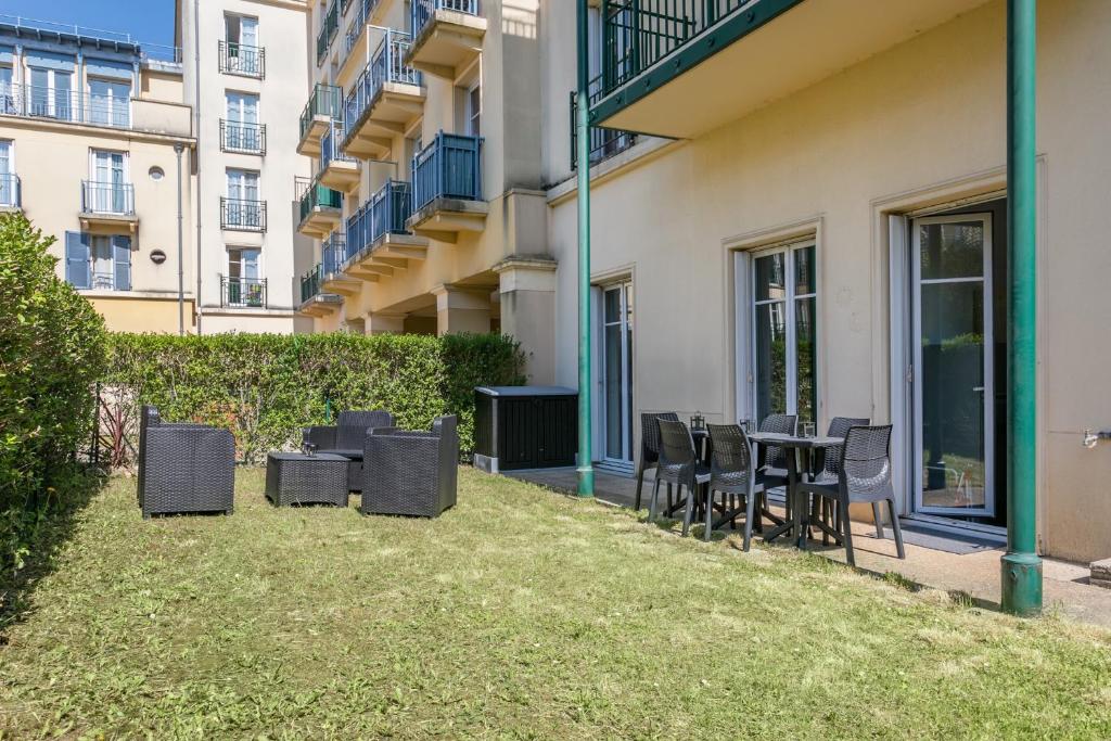 a patio with chairs and tables outside of a building at Nice Apartment Garden - 5 min DISNEYLAND Paris - Val d&#39;Europe Center in Chessy