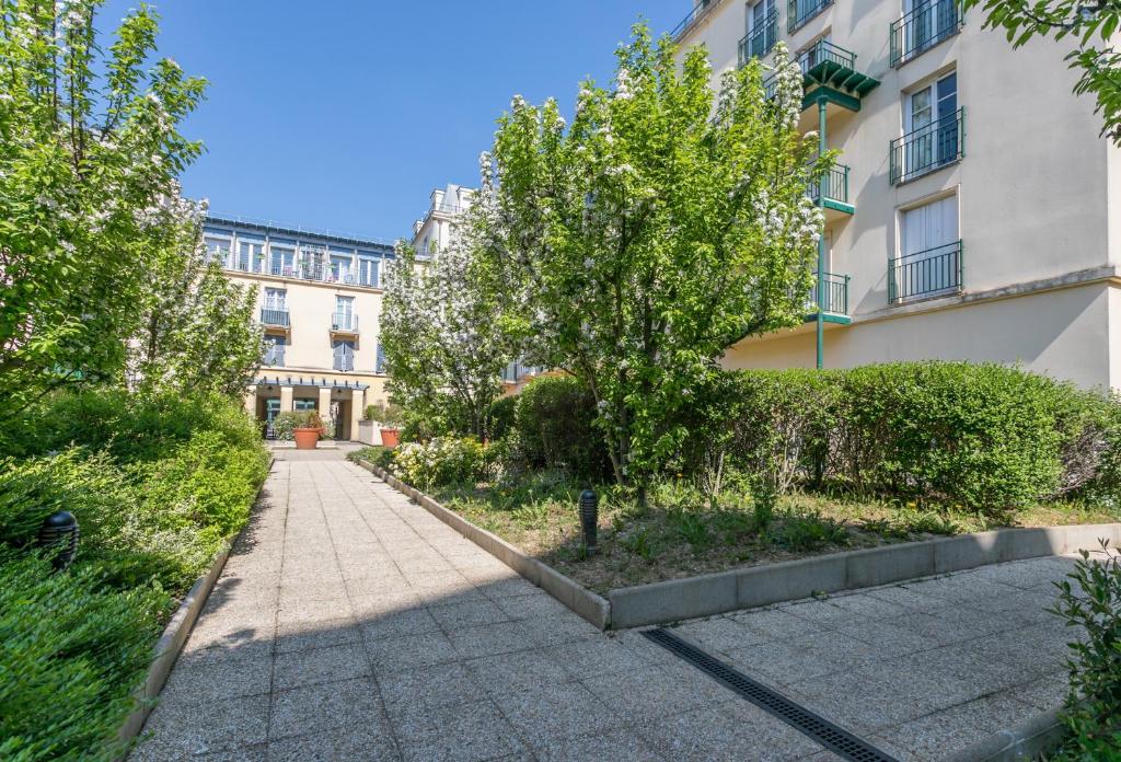 a sidewalk in front of a building with trees at Nice Apartment Garden - 5 min DISNEYLAND Paris - Val d&#39;Europe Center in Chessy