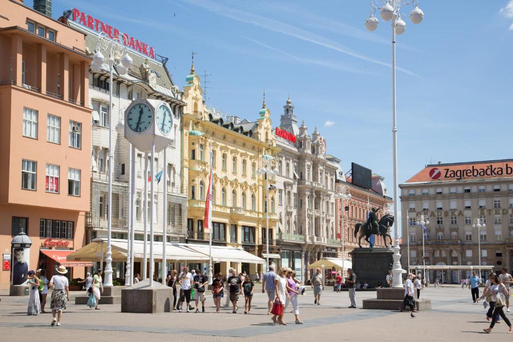 um grupo de pessoas caminhando em uma cidade com edifícios em Angel Main Square Center Zagreb em Zagreb