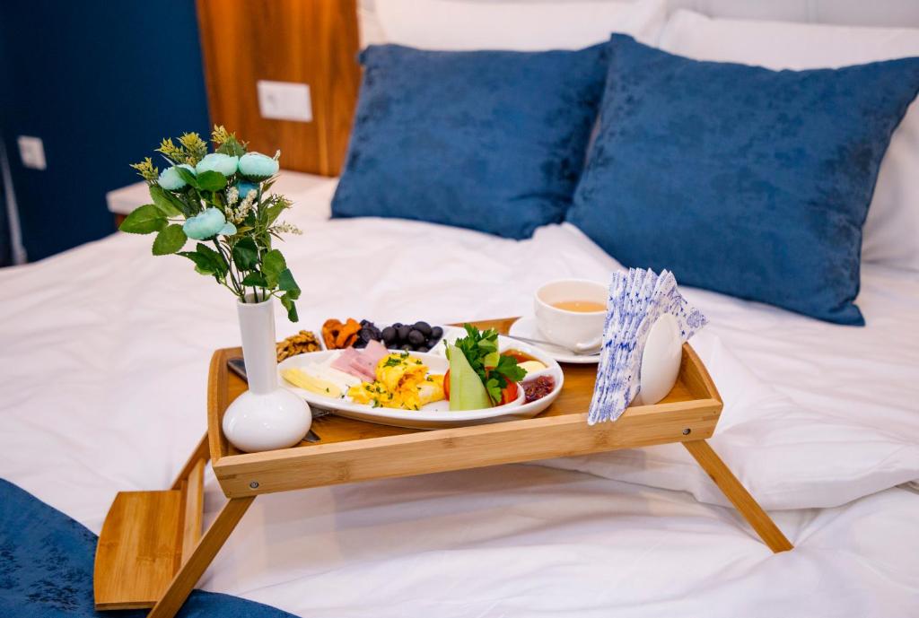 a tray with a plate of food on a bed at Aqua Batumi Hotel & Apartments in Batumi