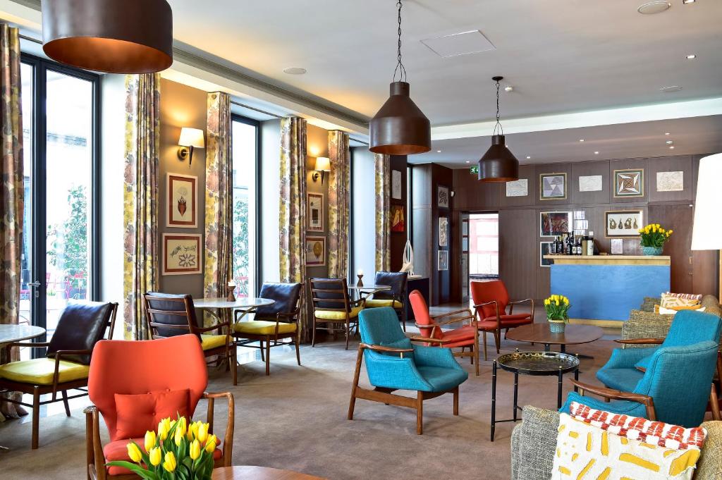 a restaurant with colorful chairs and tables and windows at The Editory Artist Baixa Porto Hotel in Porto