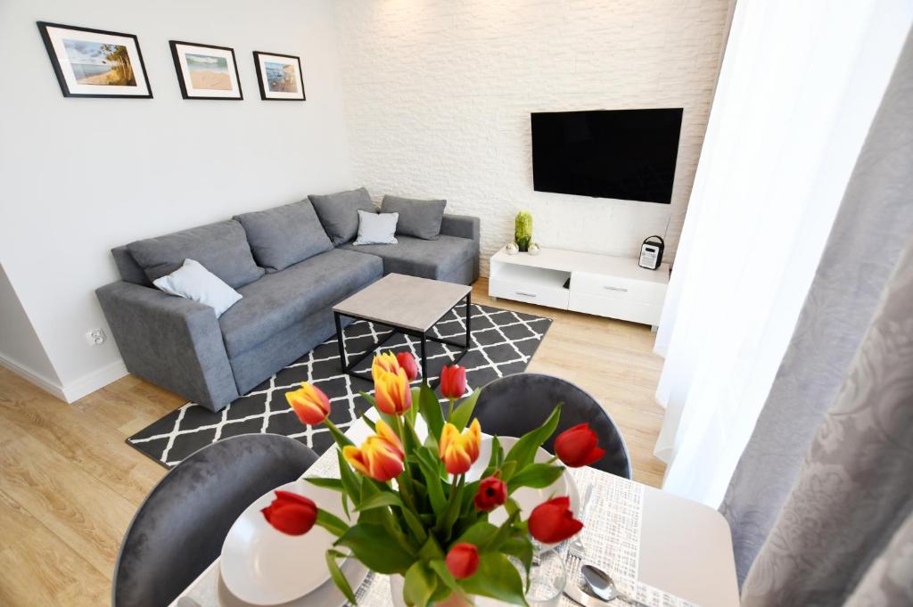 uma sala de estar com um sofá e uma mesa com flores em Apartament Baltic Pearl em Colberga