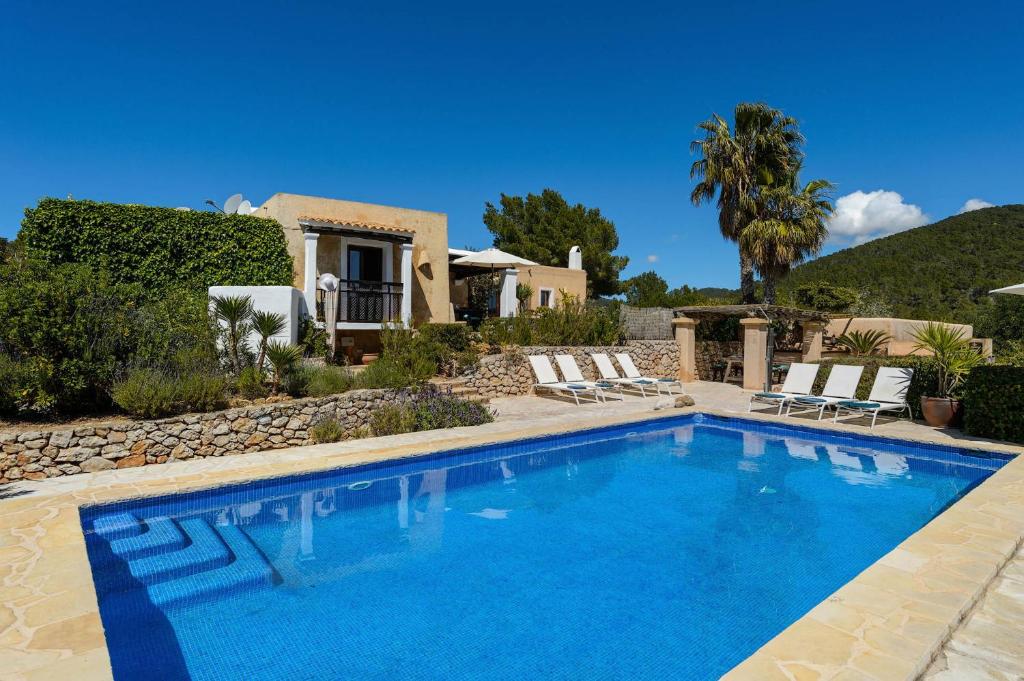 a swimming pool in front of a house at Villa Romero I in Es Cubells