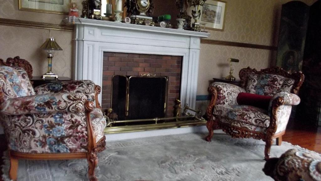 a living room with two chairs and a fireplace at Gardenvale Manor House B&B in Stranocum