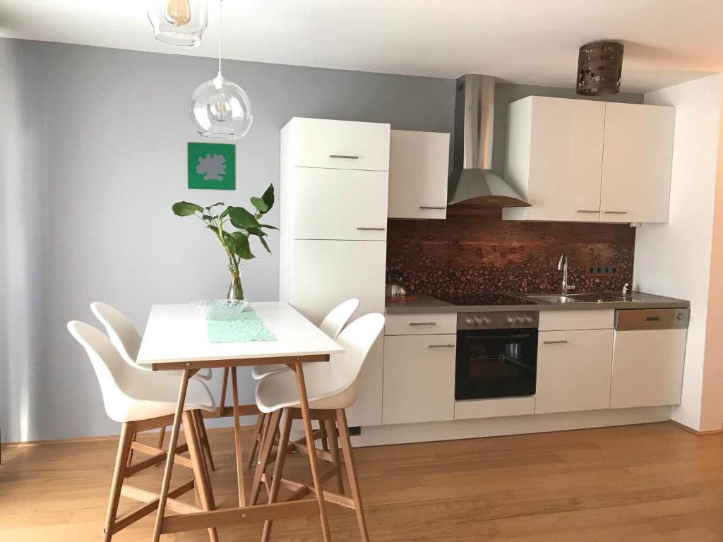 Una cocina con gabinetes blancos y una mesa y sillas. en Yellow Flower Apartment with Pool - 5 min to Lake, en Viena