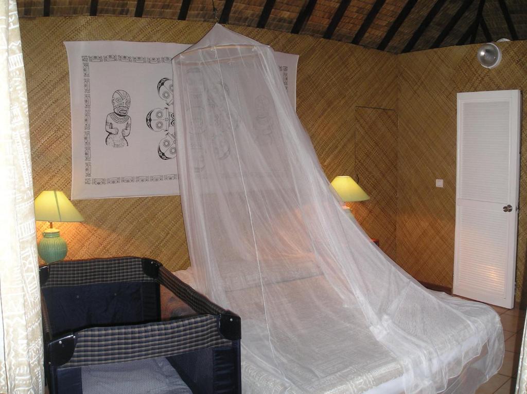 a bedroom with a bed with a mosquito net at Village Temanuata in Bora Bora
