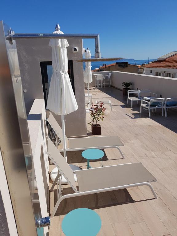 einen Balkon mit Stühlen, einem Sonnenschirm und Tischen in der Unterkunft HOTEL TORRENT in L'Escala