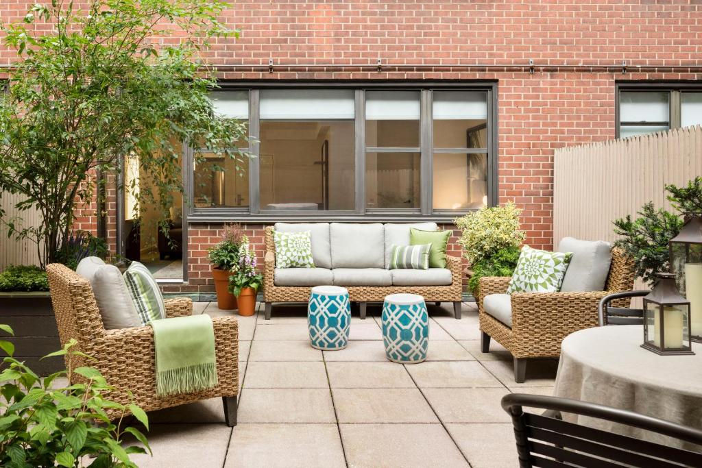 un patio con sillas de mimbre y un sofá en The Gardens Sonesta ES Suites New York, en Nueva York