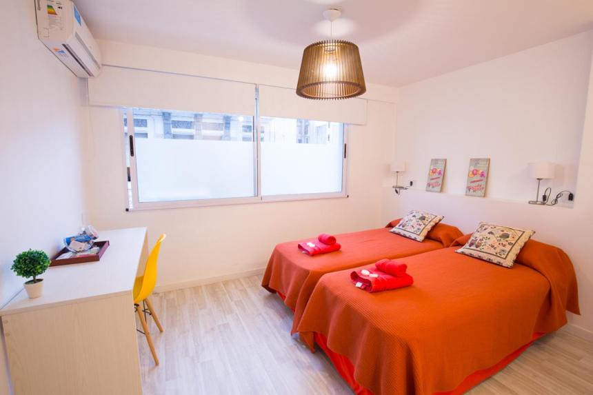 um quarto com 2 camas e lençóis vermelhos em Amazing Studio Apartment em Buenos Aires