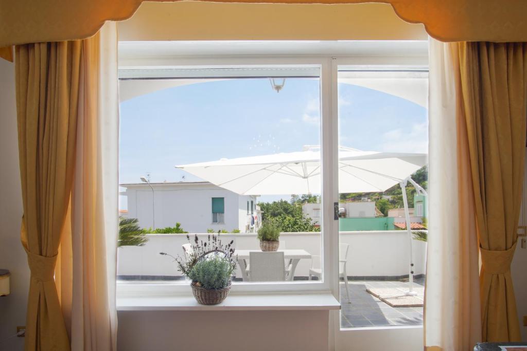 a window with a view of a patio with an umbrella at Appartamento in villa ad Ischia in Ischia