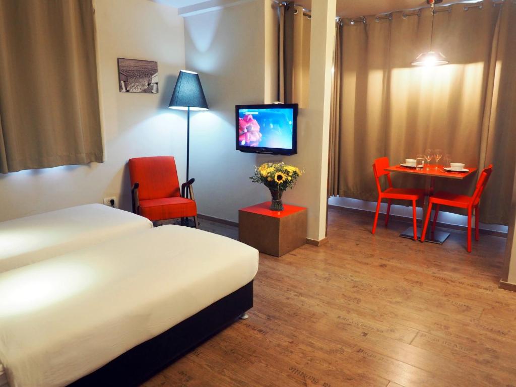 a hotel room with a bed and a table and a television at Ben Yehuda Apartments in Tel Aviv