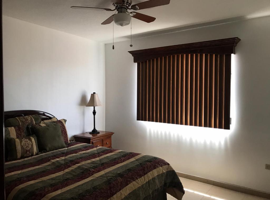 a bedroom with a bed and a window with a fan at Finca Chavez in Ensenada