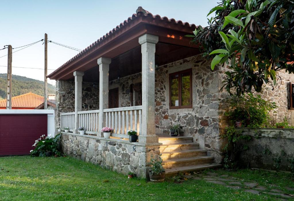 une maison en pierre avec une terrasse couverte et des escaliers dans l'établissement Casa Eido Vello, à Mos