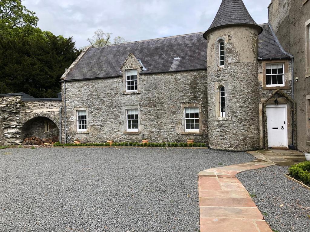 un vecchio edificio in pietra con una porta bianca di Branxholme Castle (East Wing Cottage) a Hawick