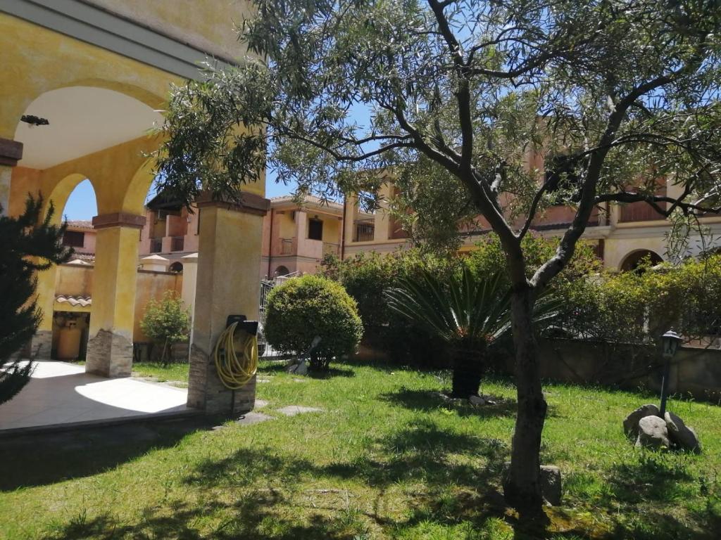 un patio de un edificio con un árbol en el césped en Casa singola ampio giardino en Villasimius