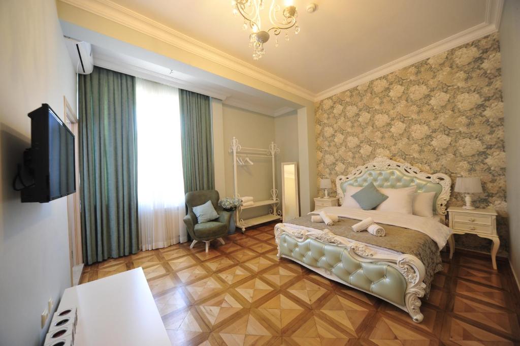 - une chambre avec un lit, une chaise et une télévision dans l'établissement Guest House Batumi Globus, à Batoumi