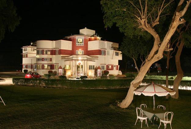 ビーカーネールにあるKarni Bhawan Palace - Heritageby HRH Group of Hotelsの大きな白い家(傘と椅子2脚付)