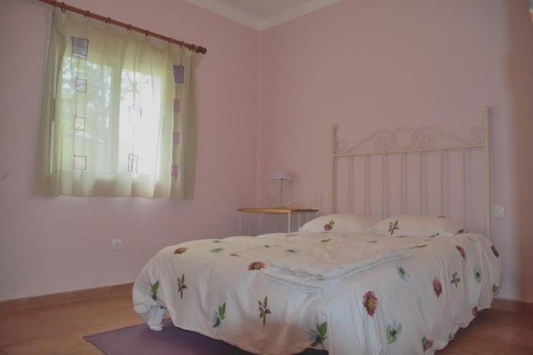 a bedroom with a bed with a white comforter and a window at Casa en plena naturaleza. in Valdecañas de Tajo